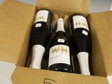 trois bouteilles de vin dans un carton sur une table