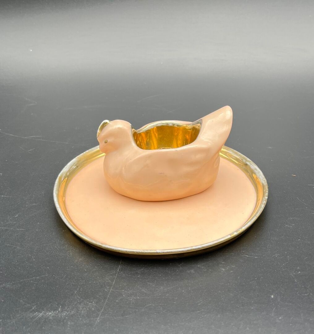 FRANCE ( LIMOGES , ) Un coquetier en forme de poule et sa coupelle en porcelaine à fond rose pâle et or. Signés au re...