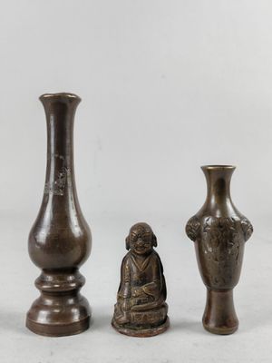 trois vases en bronze posés les uns à côté des autres sur une surface blanche