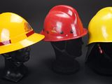 three yellow and red hard hats sitting on top of each other