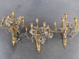 two antique brass and crystal sconces on a gray background