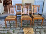 quatre chaises en bois posées sur un sol pavé, devant une porte