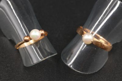 une paire de bagues ornées de perles, posées sur une surface noire
