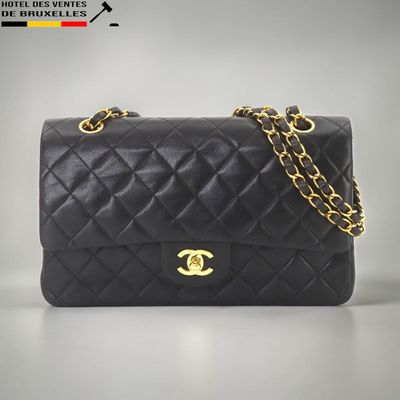 un sac Chanel noir muni d'une bandoulière en chaîne dorée