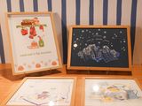 three framed pictures on a wooden table with a blue and white striped wall behind them