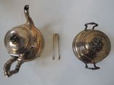 two silver teapots sitting next to each other on a table