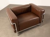 brown leather chair with chrome legs and armrests in a room