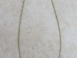 un collier en or orné d'une barre, posé sur une surface blanche