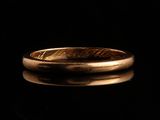 gros plan d'une bague en or sur une surface noire