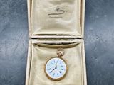 une petite montre de poche en or à l'intérieur d'un écrin en or