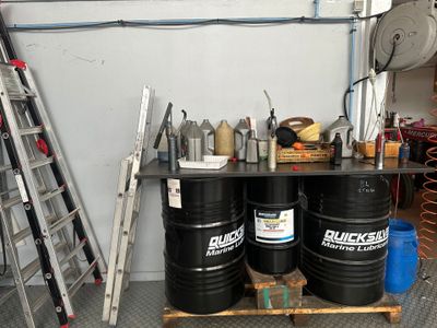 deux fûts noirs posés sur une palette à côté d'une échelle