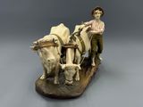 a figurine of a boy on a plow with two cows