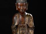 a bronze figure of a seated buddha on a black background