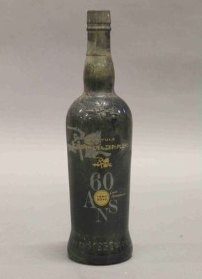 une vieille bouteille d'alcool posée sur une table blanche