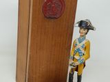 statue d'un homme en uniforme debout à côté d'une caisse en bois