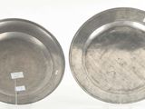 two silver plates on display on a white surface