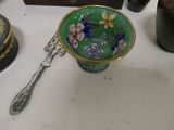 a green bowl with flowers and a spoon sitting on a table