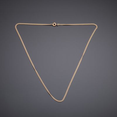 a gold necklace with a chain on a gray background