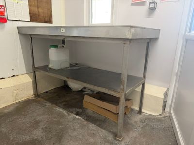 a stainless steel work table in the corner of a room