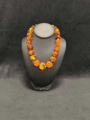 a necklace made of orange and yellow glass beads on a mannequin