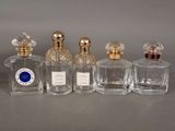 four bottles of perfume sitting on top of a table next to each other