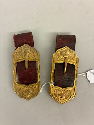 pair of antique brass buckles with red leather straps