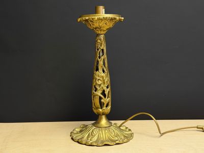 une lampe de table ancienne en laiton, avec un abat-jour blanc, posée sur une table en bois