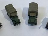 four toy trucks that are lined up on a white surface