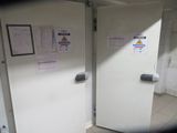 two white refrigerators in a room with papers on the wall