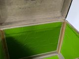 an open trunk with a green lid sitting on the floor