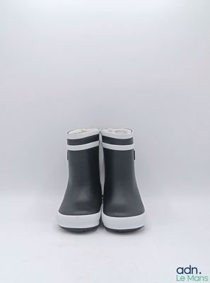 une paire de bottes de pluie noires posées sur une surface blanche