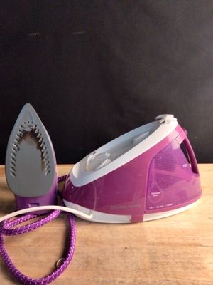 purple and white steam iron sitting on top of a wooden table next to a purple cord