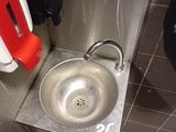a metal sink in a public restroom with a red seat