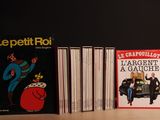 Plusieurs livres sont alignés sur une table devant un fond noir.