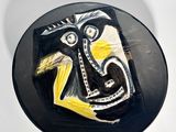 a black plate with a painting of a man on it