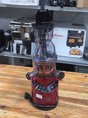 a red juicer sitting on top of a wooden table