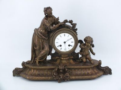 une horloge en bronze surmontée d'une statue représentant une femme et un enfant