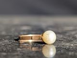 a pearl and gold ring sitting on a marble surface