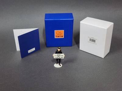 une petite figurine représentant un homme tenant une pancarte devant une boîte bleue