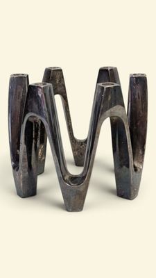 a metal sculpture of a wave on a white surface