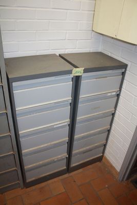 two metal filing cabinets in a room with a brick wall