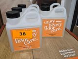 deux gallons de produit d'entretien facile pour sols posés sur une table devant une affiche