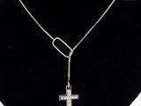 a close up of a necklace with a cross on a mannequin