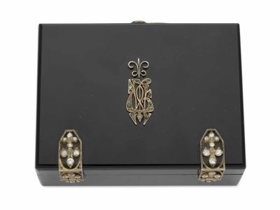 une boîte noire ornée de perles et d'un emblème en or