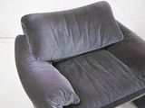 a grey chair with a pillow on it in a room
