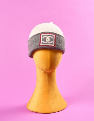 un bonnet gris et blanc sur une tête de mannequin, sur fond rose