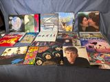plein de disques vinyles posés sur un canapé bleu