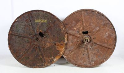 two old rusty reels sitting on top of a white surface