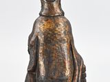 an old bronze statue of a woman sitting on a rock