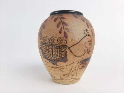 a brown vase with a bird and a basket of fruit on it